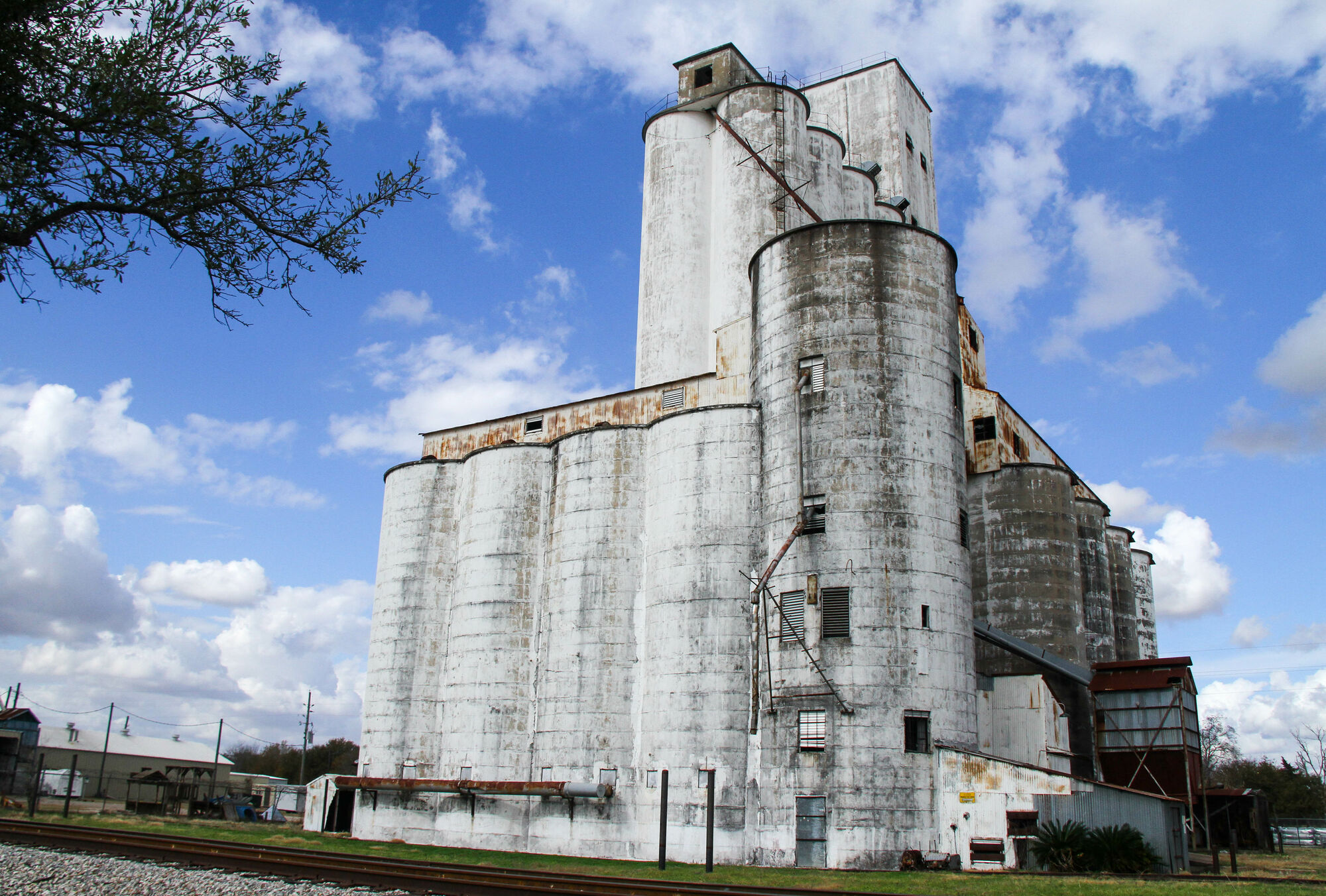 The white concrete rice dryers of The Dryer under a blue sky with clouds