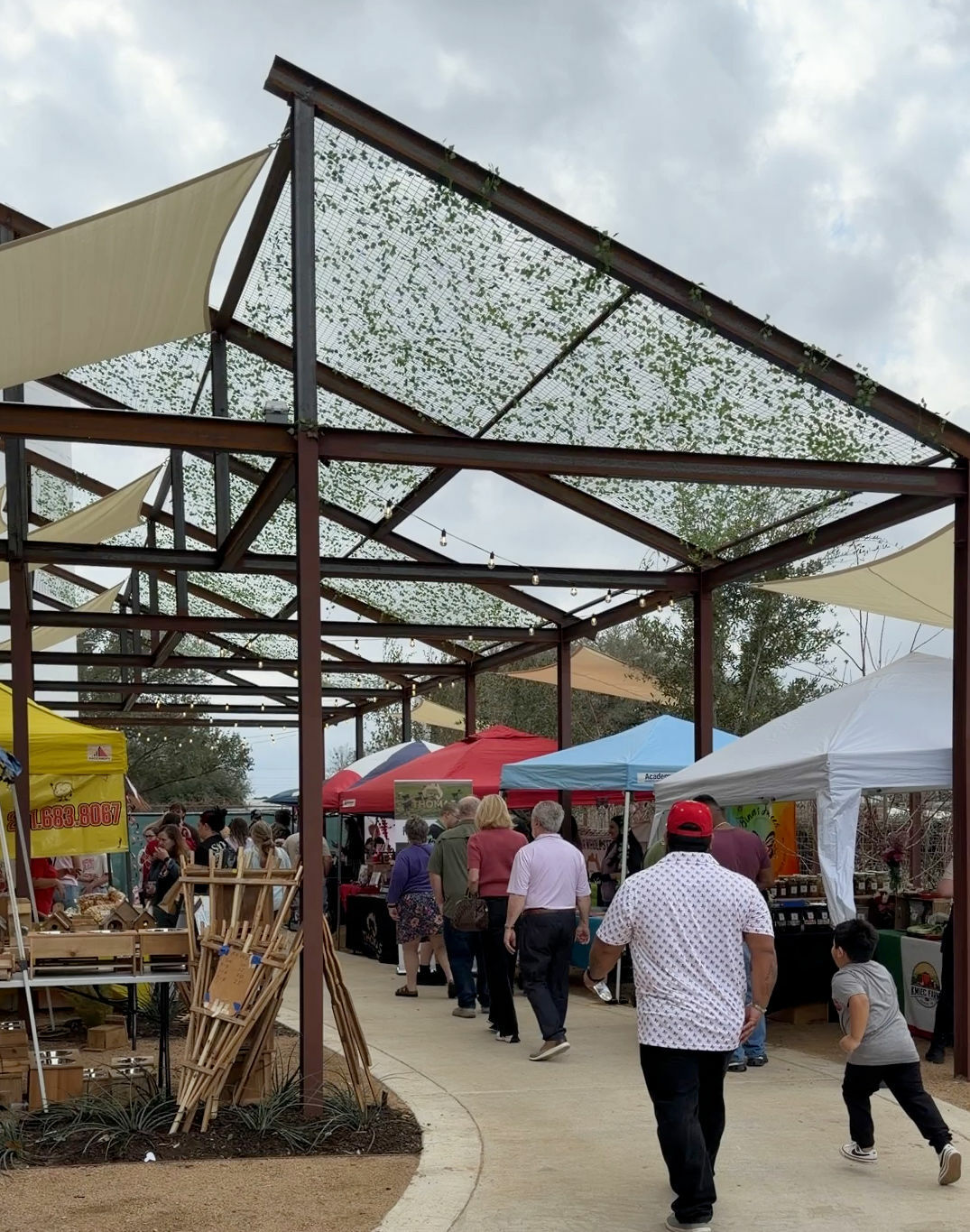 People walking under a steel pergola at the market